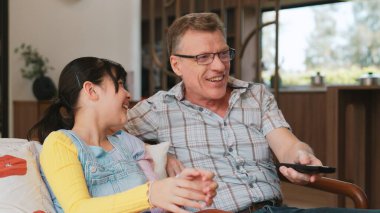 Grandfather and granddaughter together watch interesting entertainment media on TV. Old senior use technology communicate with young generation cross generation gap strengthen family bond. Divergence. clipart