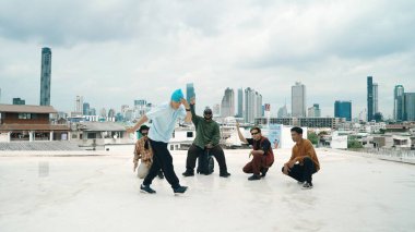 Profesyonel break dans takımı çatıda çok kültürlü arkadaşlar varken break dans alıştırması yapıyor. Genç modern dans grubu hip hop hareketi yapıyor. Tarz, moda, aksiyon. Açık hava sporu 2024 hiphop..