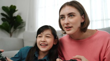 Kafkas anne ve kızı oturma odasında oturup oyun oynuyorlar. Mutlu anne, elinde joystick tutarken akıllı Asyalı kızla vakit geçiriyor. Oyun oynamaktan zevk alıyor. Yaşam tarzı konsepti. Pedagoji.