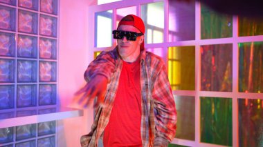 Kafkas dansçısı dans ederken çeşitli arkadaşları gece kulübünde neon ışıkta ayak seslerine bakıyor. Çoklu etnik kökenli hipsterin serbest stil müziğe geçişi ve mutlu bir adamın kameraya bakışıyla. Mutluluk.