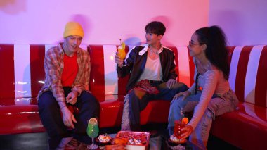 Takım çalışmalarını kutlamak için neon lambalı çok kültürlü bir arkadaş bardak tokuşturuyor. Renkli meyve suyu ve tokuşturarak şık modaya sahip profesyonel çeşitli insanlar. Mutluluk.