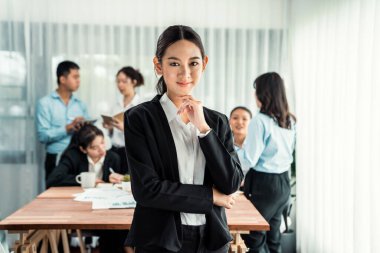 Kameraya bakan mutlu Asyalı genç iş kadını portresi dinamik iş görüşmelerinde iş insanlarının hareketlerinin hareket bulanık arka planına sahip. Habiliment