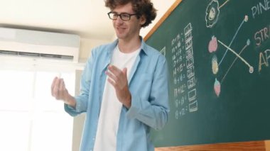 Öğrenciye bakarken, sınıfta matematik teorisi hakkında konuşan ve açıklayan beyaz bir öğretmen. Tahtanın önünde durup tahtaya işaret eden yetenekli bir eğitmen. Pedagoji.