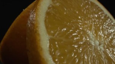 Portakal diliminin bir makrografi görüntüsü, parlak, izole edilmiş bir arkaplan üzerine yerleştirilmiş, narenciye cazibesinin görsel bir başyapıtı olarak gözler önüne seriliyor. Siyah arkaplanlı bir dilim portakal. Geliştirilebilir.