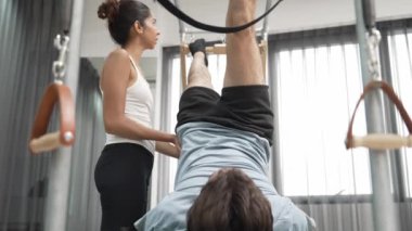 Pilates hocası bir müşteriye Cadillac 'ta bacak kaldırma egzersizinde rehberlik ediyor. Sağlıklı bir adam, çekirdek dayanıklılığını ve esnekliğini arttırmak için Cadillac 'ın üzerinde ters bacak daire çiziyor. Alışkanlık.
