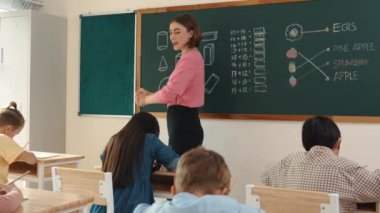 Profesyonel mutlu öğretmen sınıfta oturan çeşitli mutlu öğrencilerden not defteri toplar. Kafkas hocası sınıfta dolaşırken çocukların ödevlerini topluyor. Eğitim konsepti. Pedagoji.