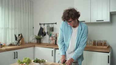 Mutlu baba yemek pişirirken müziğe geçiyor ve modern mutfakta öğle yemeği hazırlıyor. Aktif baba, sebze ve mutfak gereçleri ile çevrili sağlıklı yemek ya da salata yaparken şarkıyla dans ediyor. Pedagoji.