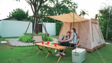 Aile hep birlikte bahçedeki kampta oturup yemek yiyor. Ebeveynler, genç nesil arasında iletişim kurmak ve zaman geçirmek için açık hava kamp faaliyetlerini kullanıyorlar. Uyumsuzluk.