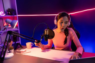 Geceleri podcast 'te olumlu konuşmalar yapan, pembe neon ışıklı modern stüdyoda sunum için dizüstü bilgisayar kullanan, gülümseyen, genç, güzel Asyalı bir etkileyiciydi. Taktik.