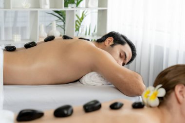 Lüks tatil köyündeki kaplıca salonunda sıcak taş masajı. Gündüz dinginliği ortam, mutlu çift müşterileri bazalt taşı masajının keyfini çıkarıyor. Rahatlatıcı bir sıcaklıkla vücudun üzerinde süzülüyorlar. Sessiz.