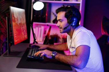 Akıllı oyun flaması dijital neon ışıklı siber odada kulaklık takarak bilgisayar ekranında çoklu ya da tek oyuncuyla çevrimiçi atış oyunu oynayan bir savaş takımı ile oynamaktan zevk alır. Tahmin et..