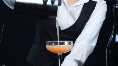 Akıllı barmene yakın dur. Barda ve modern barda portakal ve biberiyeyle kokteyl hazırla. Profesyonel barmen elleri siyah arka planda kan turuncu negroni yapıyor. Ağır çekim. Geliştirilebilir.