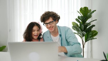 Beyaz bir baba kızına kulaklık takarken kız da kod öğreniyordu. Babam, mühendislik öğretirken liseli kızla ilgilenir ve dizüstü bilgisayar kullanarak Ai üretir. Çevrimiçi öğrenme. Pedagoji.