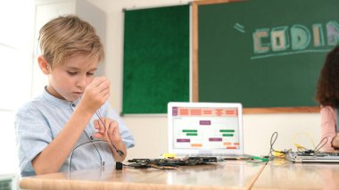 Kız tornavida kullanarak elektronik tahtayı tamir ederken ayakta duruyor. Amerikalı öğrenci ve beyaz çocuk elektrik sistemini denetlemek için birlikte çalışıyorlar. Gemide çalışan meraklı çocuklar. Pedagoji.