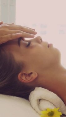 Lüks bir spa merkezinde masaj terapisti tarafından yüz masajı ve spa tedavisi için kaplıcaya uzanmış rahat bir kadın. Sağlık, stres atma ve gençleştirme kavramı.
