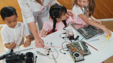 Kafkas öğretmeninin en iyi görüşü öğrencilere dijital elektrikli aletleri öğretmek ve açıklamak. Kız elektronik aletleri öğreniyor ve ana kartı tamir etmek için çipleri ve kabloları yerleştiriyor. Etkinlik.