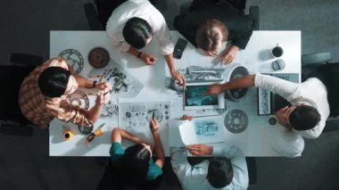 Üstten görünüşlü akıllı mühendis ekibi metal teçhizatlı, hesap makineli, yapışkan notlu türbin motor yapısı hakkında konuşuyor. Bir grup teknisyen toplantıda not alıyor. Hizalama.