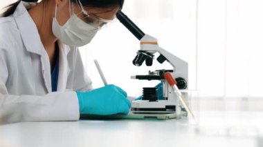 Laboratuvar kimya araştırmacısı mikroskop kullanarak yeni ilaç ya da tedavi geliştirir. Laboratuvar mikrobiyoloji ekipmanları ile bilimsel uzmanlık ile sağlık hizmetlerinin teknolojik gelişimi. Ağır çekim. Katı.