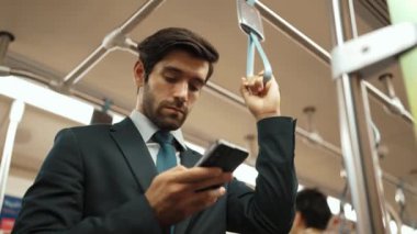 İş adamının elleri trende insanlarla çevriliyken telefona bakarken yakın çekim. Kafkas proje yöneticisi e-postaları kontrol ediyor, arka planı bulanık pazarlama stratejisi planlıyor. Sevinçli..