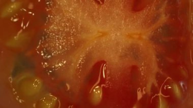 Dilimlenmiş domatesin makro fotoğrafı. Domates eti sulu ve yumuşak görünüyor, hafif bir sertlikle. Dilimlenmiş domates ışığın altında parlıyor, tazeliklerini ve olgunluklarını gösteriyor. Geliştirilebilir.