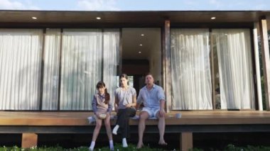 Şirin baba, anne ve kızı birlikte evin bahçesinde oturuyorlar. Ebeveynler, çevre farkındalığıyla ilgili genç nesli iletişim kurmak için açık hava aktivitelerini kullanırlar. Uyumsuzluk.