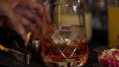 Yakın plan el yapımı barmen karışık alkollü likör şurubu karıştırıp buzla karıştırıyor. Barda eski moda kokteyl tatma kokteyli hazırlıyor ve gece hayatı karışımı sergiliyor. Vinosity.