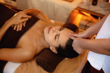 Beyaz kadın stres önleyici kafa masajı yapmaktan ve lüks otel veya otelde sıcak mum ışığında yüz güzelliği eğlencesi yapmaktan zevk alıyor. Sessiz.