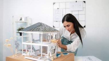 Genç, beyaz, güzel mimar mühendisi ev modelini ev inşaatını teftiş etmek ve sorunu modern ofisteki toplantı masasında çözmek için hata noktasını kontrol etmek üzere çeviriyor. - Yakın çekim. Tertemiz..