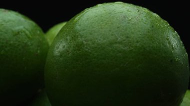 Slices of lime are meticulously arranged in a pile, set against a black background. Each lime slice is captured in stunning detail, its vibrant green hue and enticing texture. Close up. Comestible. clipart