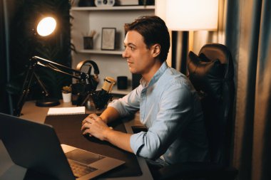 Sunucu kanalı akıllı yayıncı laptopta canlı sosyal medya uygulaması arıyor, kulaklık takıyor ve modern ofis stüdyosundaki mikrofonu kullanıyor. Bireysel.