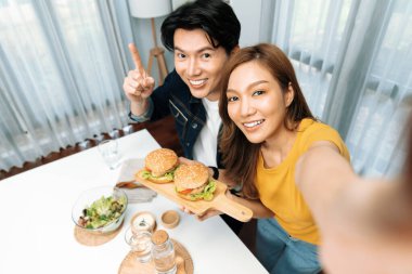 Gülümseyen ev sahibi aşçıların akıllı telefonuyla fotoğraf çekerken üst görüntüsü yemek programında çift hamburger tutarken sosyal medya kanalında ev yapımı salata tabağıyla kolaylıkla görülebiliyor. İnfobahn.