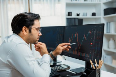 Akıllı tüccar işadamı, modern merkez ofisindeki araştırma pazarında en yüksek kârlı finansal teknolojiye yatırım yaparak bilgisayar üzerinde iki dinamik borsa yatırım ekranını analiz ediyor. Tahmin et..