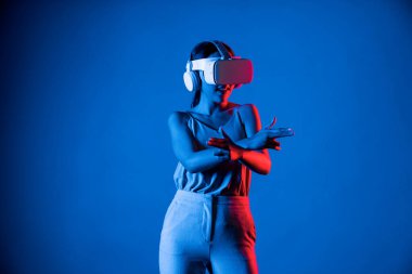 VR kulaklık takan zeki bir kadın metaevrene bağlanıyor, gelecekteki siber uzay topluluğu teknolojisi. Sanal silaha hükmeden zarif bir kadın ciddi ciddi oyun oynuyor. Halüsinasyon.