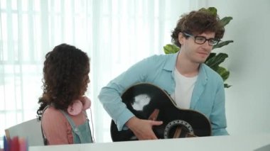 Beyaz bir baba gitar çalar ve müziğe yönelirken Amerikalı kız da akustik şarkı eşliğinde el sallar ve dans eder. Mutlu aile evde birlikte vakit geçirir. Yaratıcı aktivite konsepti. Yaşam tarzı. Pedagoji.