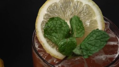 Makrografi, bir dilim limon ve taze naneyle süslenmiş Tekila Sunrise kokteyli, dramatik bir siyah arkaplan üzerine kurulmuş. Yakın çekim kokteylin canlı renklerini yakalar. Geliştirilebilir.