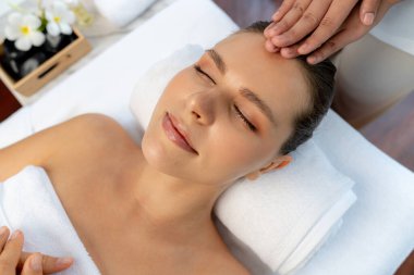 Kafkasyalı kadın stres önleyici kafa masajından ve lüks tatil beldesi ya da otel spa salonundaki modern ışık ortamında yüz güzelliği eğlencelerini şımartmaktan hoşlanıyor. Sessiz.