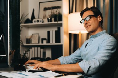 Akıllı iş adamı iş paragrafı dinamik pazarlama analizi planını analiz ediyor. Kağıt kağıtları ve bilgisayar monitörü raporlarını gece evdeki belge verileriyle karşılaştırmak için hazırlıyor. Bireysel.