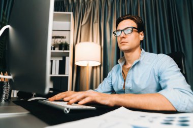 Akıllı iş adamı iş paragrafı dinamik pazarlama analizi planını analiz ediyor. Kağıt kağıtları ve bilgisayar monitörü raporlarını gece evdeki belge verileriyle karşılaştırmak için hazırlıyor. Bireysel.