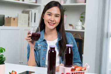 Gülümseyen, güzel Asyalı genç, lezzetli karışık çilek ve kiraz suyu detoksu içeceklerini inceleyen, sosyal medyada özel promosyon satışı için sağlıklı ürünler sergileyen. Taktik.