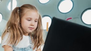 Bilgisayarda çalışan ya da online sınıfta okuyan öğrencilere yakın çekim. Ev ödevi yaparken ya da müzik dinlerken dizüstü bilgisayarda yazan tatlı bir kız. Kulaklık takan küçük bir çocuk. Yaratıcı öğrenme. Etkinlik.