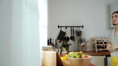 Mutlu genç anne mutfakta dururken salata kasesine sebze koydu. Çekici beyaz bir kadın yemek pişirmekten ve sabah taze organik yemek yapmaktan ya da ev yemeği yapmaktan zevk alır. Pedagoji.