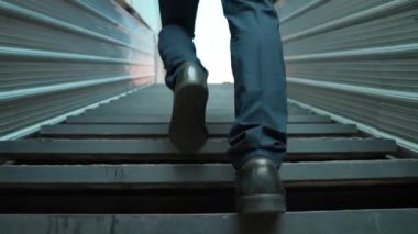 Merdivenlerden çıkan başarılı iş adamının bacağına yakın plan. Müdürün iş yerini değiştirmesi, yeni bir şey keşfetmesi, gelişmesi, terfi etmesi ya da gün ışığına çıkması. Yükseliyor. Bacağa odaklan. Sevinçli..