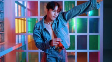 Kameraya bakarken kollarını esneten seksi kıyafetli Asyalı dansçı. Profesyonel sanatçı gece kulübünde renkli neon ışıkları canlı bir şekilde dururken serbest stil dansı yapıyor. Mutluluk.