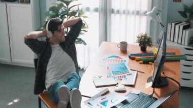 Kafadan aşağı rahatlamış yöneticinin kahve içerken tasarım renginin görüntüsü. Müzik dinlerken kulaklık takan akıllı iç mimarın hava görüntüsü ve bacağı toplantı masası sempozyumuna koy.