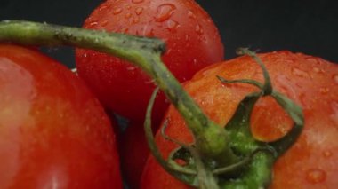 Makrografi, ahşap bir sepete yerleştirilmiş domatesler dramatik bir siyah arka plana karşı sergileniyor. Her yakın çekim domateslerin zengin renklerini ve dokularını yakalar. Geliştirilebilir.