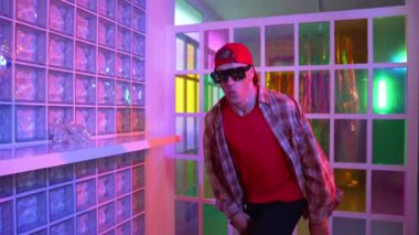 Yakışıklı, beyaz tenli sanatçı kurşun ışıkla dans etmek için dans ediyor. Güneş gözlüklü, şapkalı çılgın hippi dans ediyor ve modern gece kulübünde serbest dans dinlemenin tadını çıkarıyor. Mutluluk.