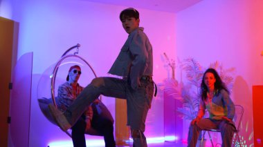 Çok kültürlü bir arkadaş kürsüde otururken Asyalı yetenekli bir dansçı modern müziğe geçiyor. Profesyonel dansçı, hipster takımı tezahürat yaparken ve desteklerken enerjik adımlar atıyor. Mutluluk.