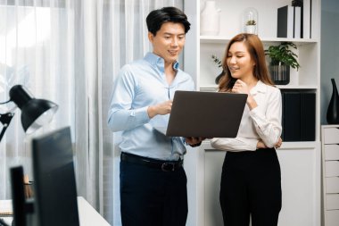 Gülümseyen Asyalı iş arkadaşları modern ofiste dizüstü bilgisayar pazarlama projesi hakkında konuşurken. Yeni sosyal medya kanalında başarılı müşteri ihtiyaçları analiz ediliyor. İnfobahn.
