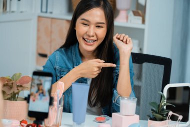 Genç, güzel Asyalı kozmetik makyaj ruju matte pastel rengini modern odadaki sosyal medyada kol testi tanıtımında en çok satanlar listesinde gösteriyor. Taktik.