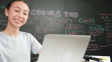 Kara tahtada dizüstü bilgisayar kullanarak akıllı kız programlama sistemi. Lise öğrencisi mühendislik kodları yazıyor ya da STEM teknoloji sınıfındaki kameraya bakarken bir şey söylüyor. Yaratıcı eğitim. Öğretim